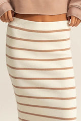 Beige and brown striped skirt worn with a beige top on a plain background