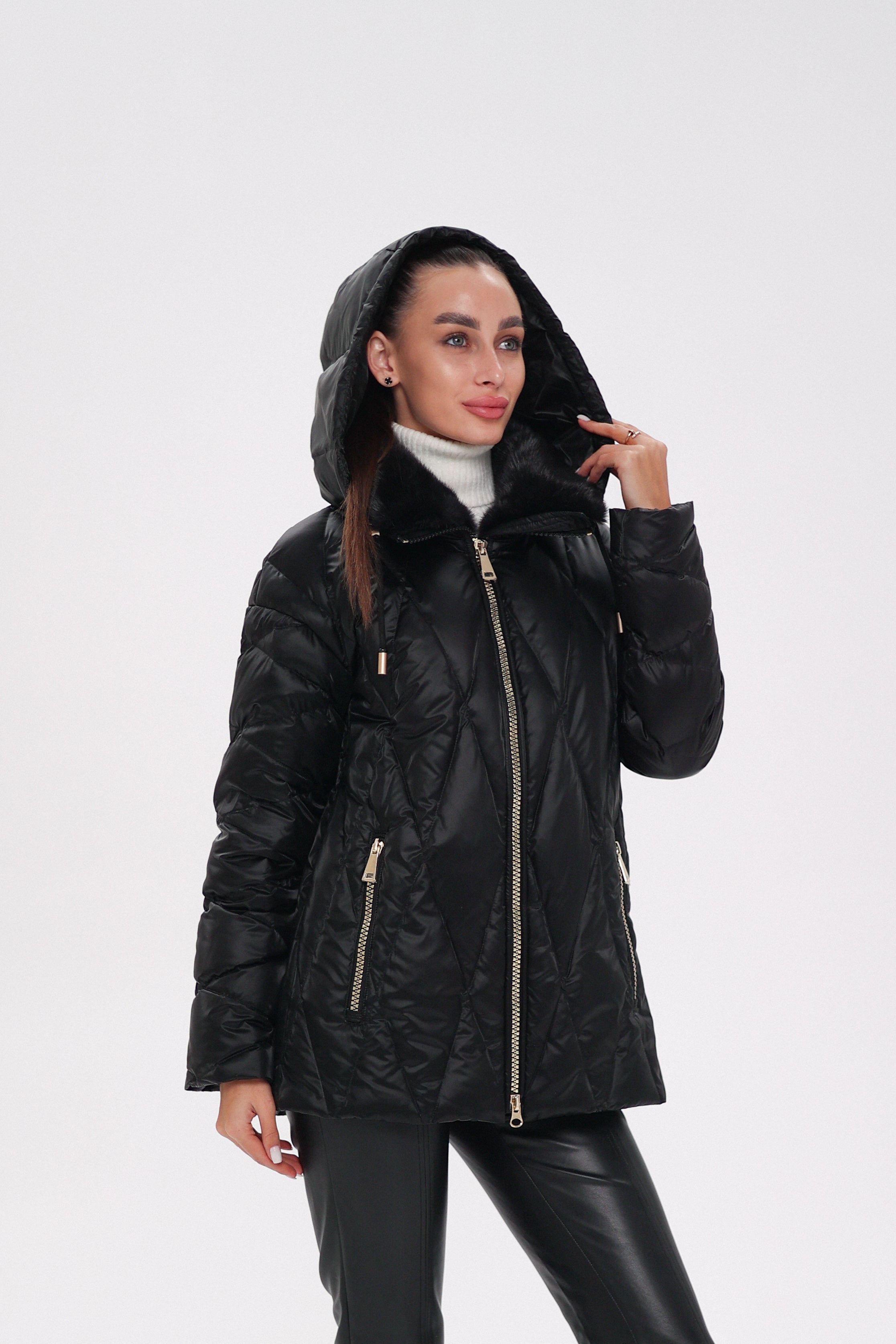 Woman wearing a black quilted jacket with a hood on a white background