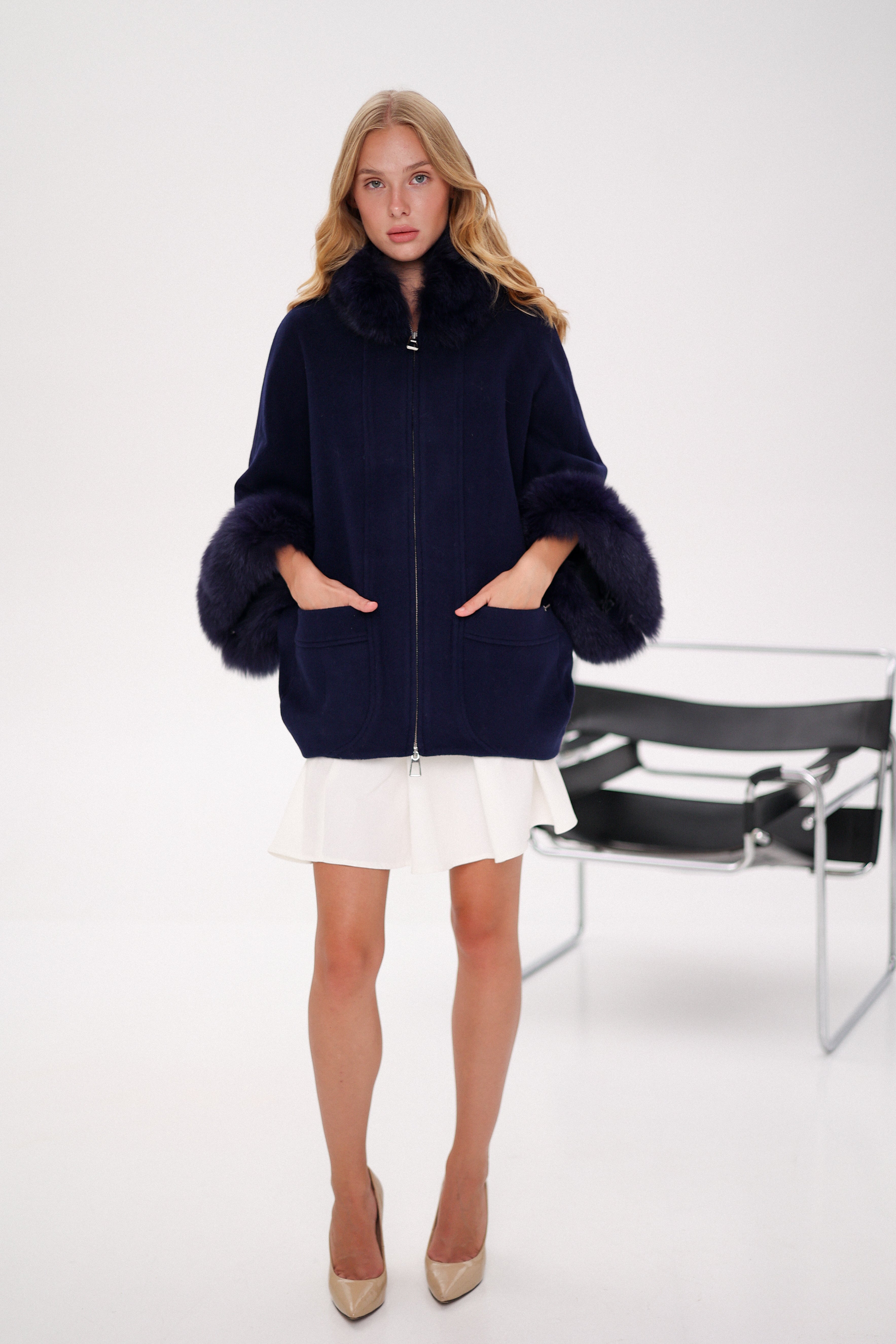 Woman wearing a navy blue coat with fur trim on a white background
