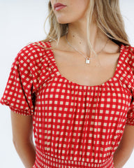 Red and white checkered dress worn by a person on a plain background