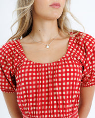 Red and white checkered top worn by a person on a white background