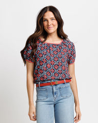 Woman wearing a floral blouse and jeans on a plain background