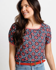 Woman wearing a floral patterned top with red accents on a white background