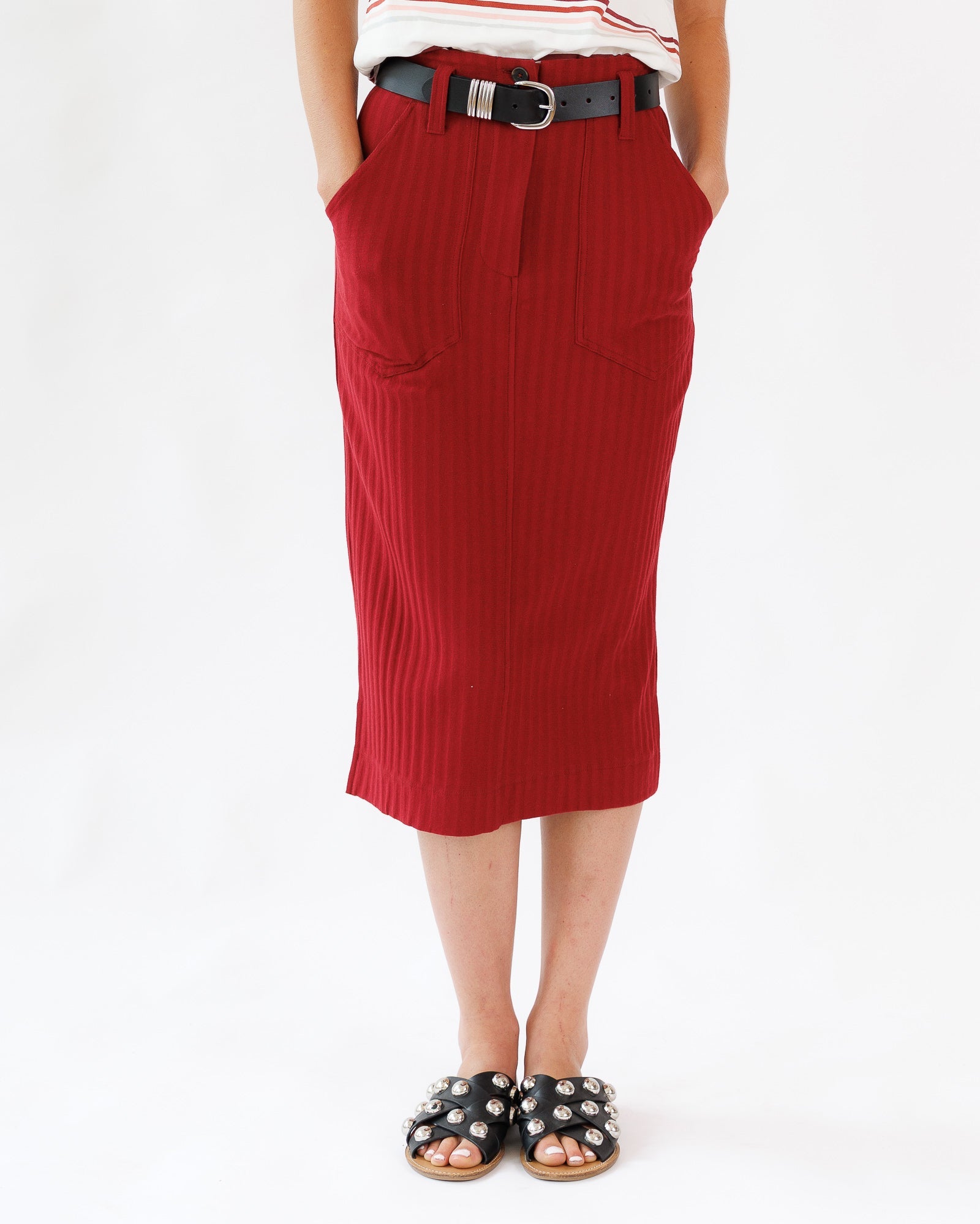 Person wearing a red skirt with a belt on a white background