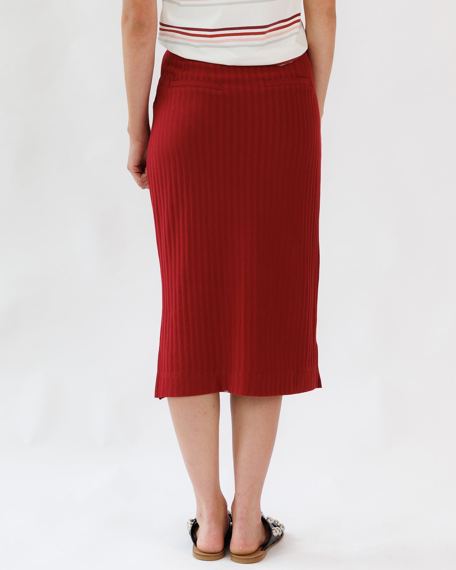 Person wearing a red ribbed skirt on a white background