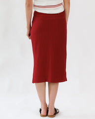 Person wearing a red ribbed skirt on a white background