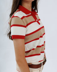 Person wearing a red and beige striped polo shirt against a white background