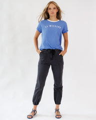 Woman wearing a blue t-shirt with 'Le Week-end' text and black pants on a white background