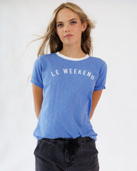 Woman wearing a blue 'Le Weekend' t-shirt against a white background