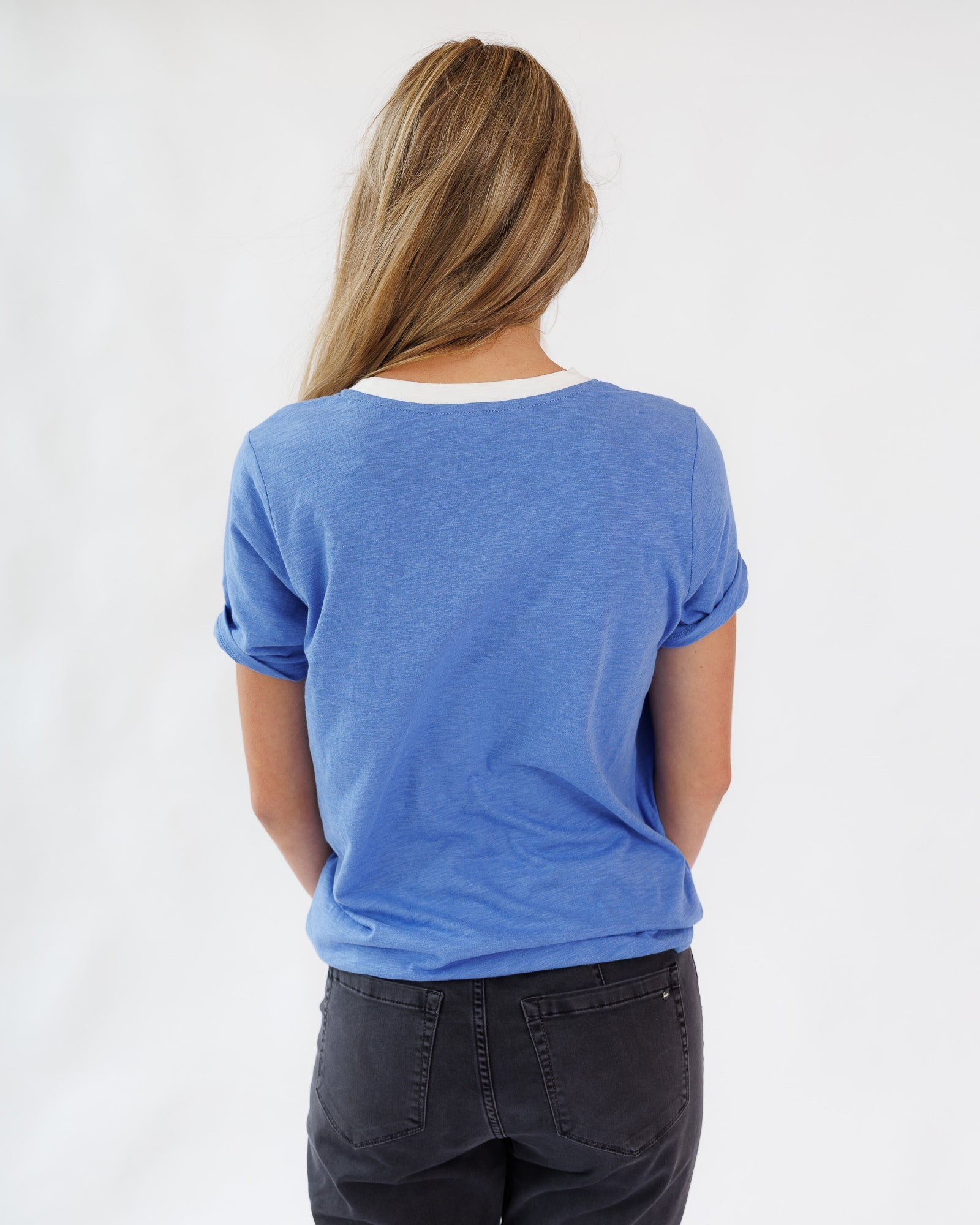 Person wearing a blue t-shirt and dark pants on a white background