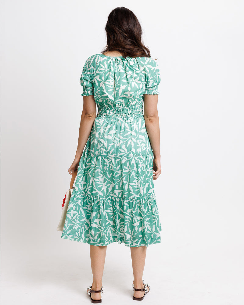 Woman wearing a green leaf-patterned dress on a white background