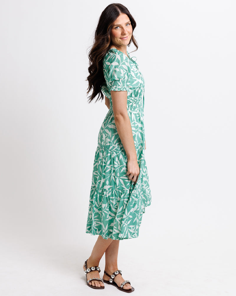 Woman wearing a green leaf-patterned dress on a white background
