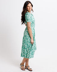 Woman wearing a green leaf-patterned dress on a white background