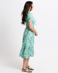 Woman wearing a green leaf-patterned dress on a white background
