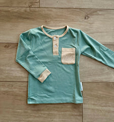 Green long-sleeve shirt with beige accents on a wooden surface