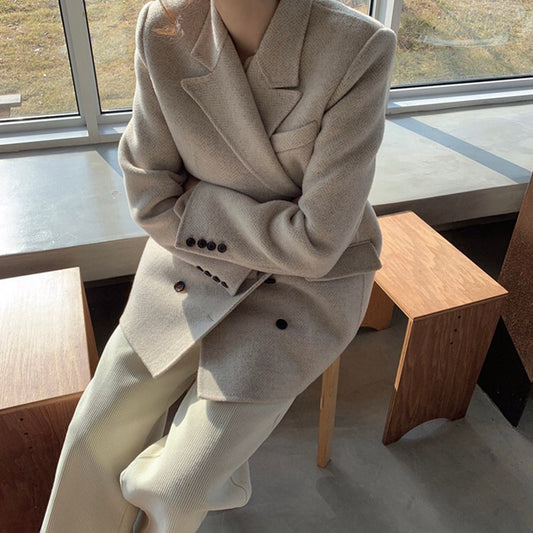 Person wearing a beige suit sitting on a wooden bench indoors.