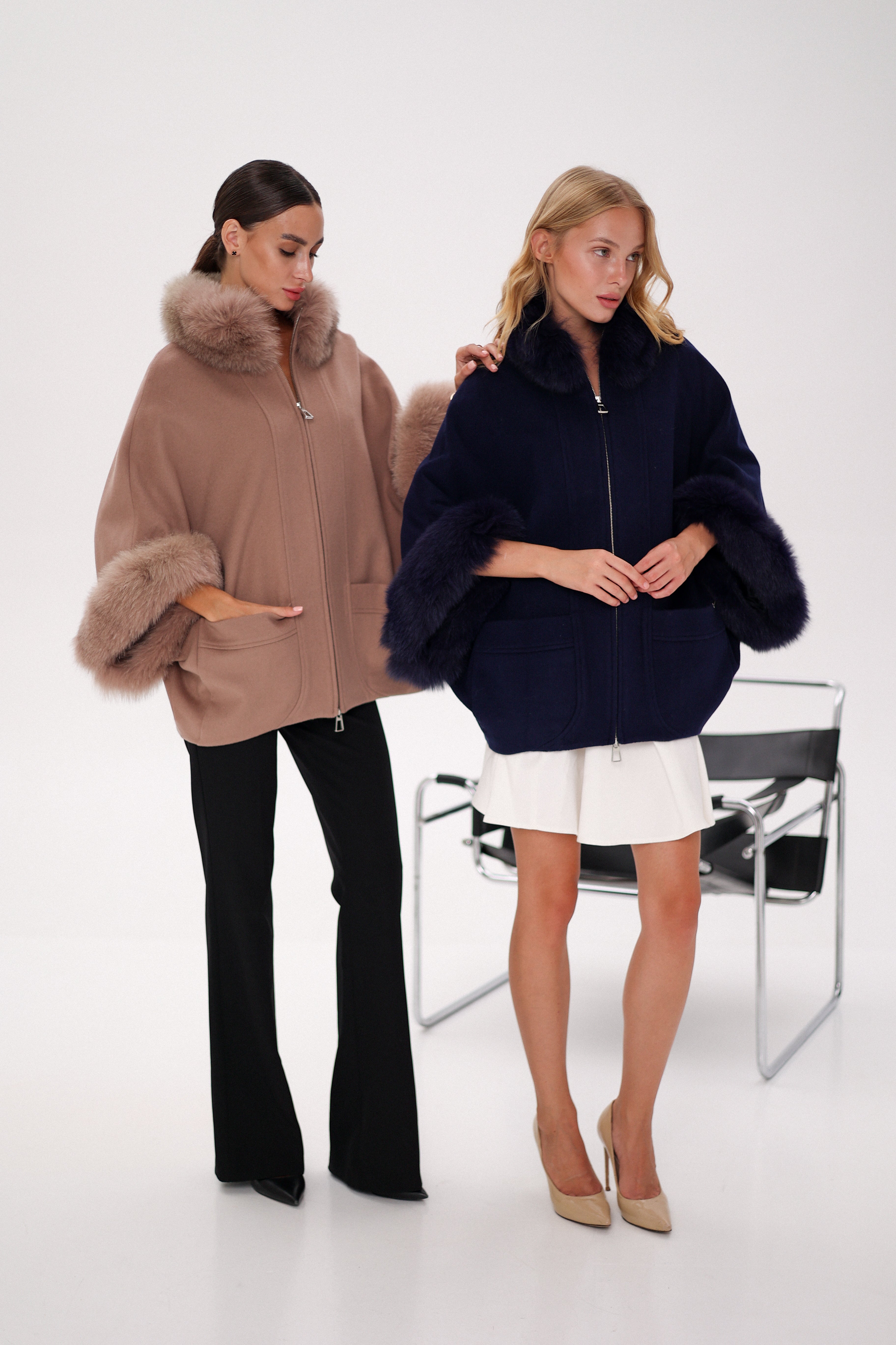 Woman wearing a navy blue coat with fur trim on a white background