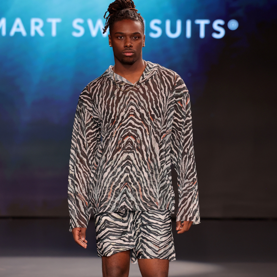Model wearing a zebra print outfit on a runway with 'Smart Swimsuits' branding.