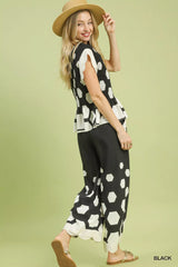 Woman wearing a black and white patterned top and pants on a green background