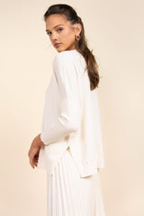 Woman wearing a white outfit against a beige background