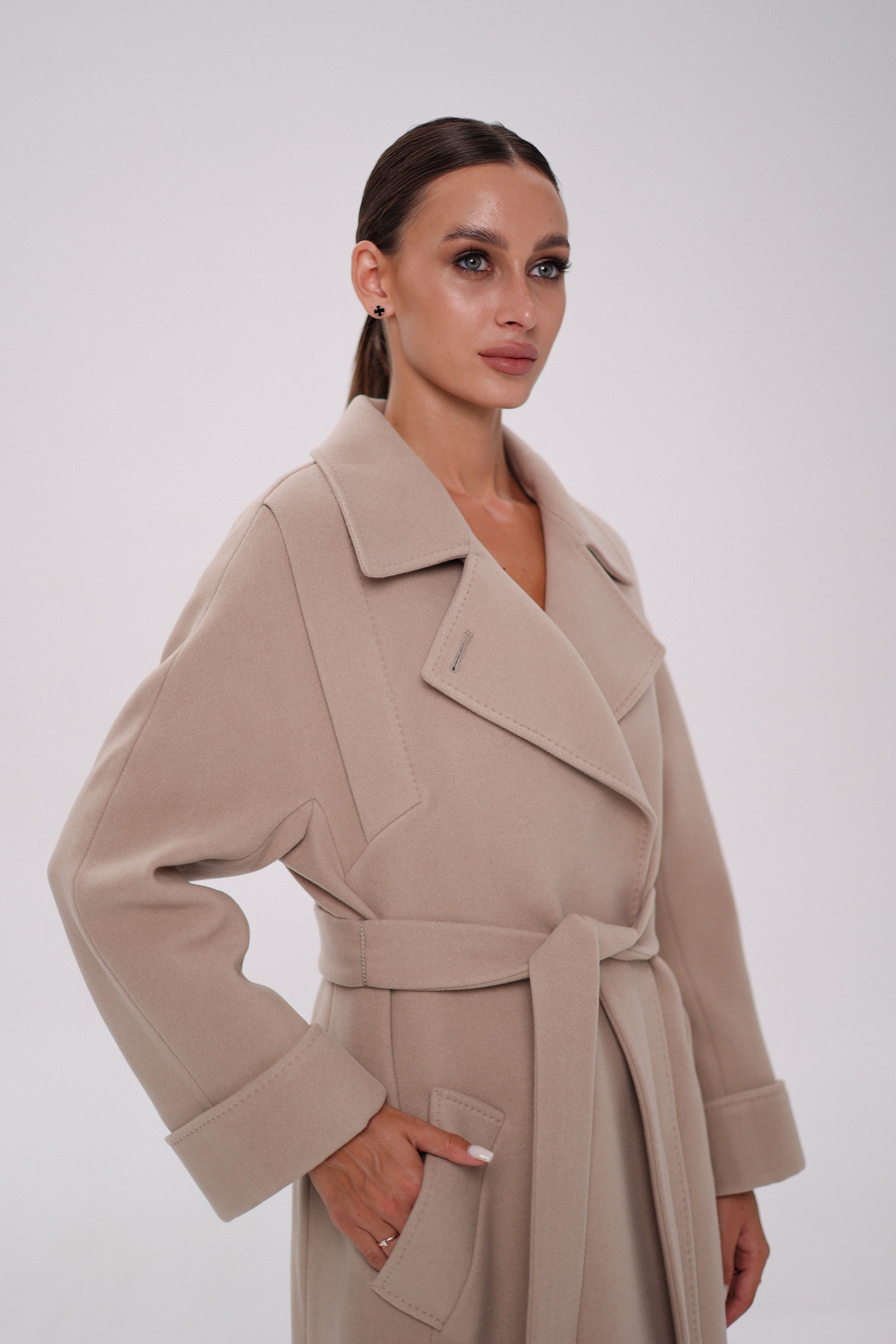 Woman wearing a beige trench coat against a white background