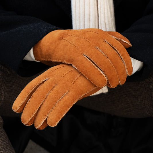 Brown leather glove held by a person wearing a dark coat and white shirt.