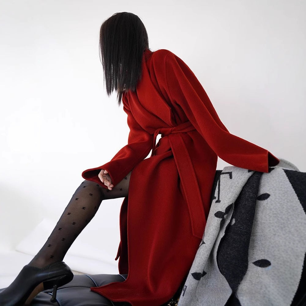 Person wearing a red coat sitting on a chair with a white background