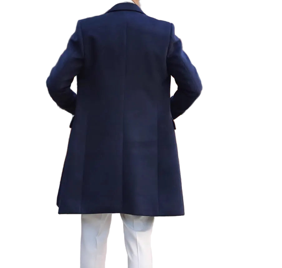 Person wearing a navy coat walking away from a building with wooden doors.