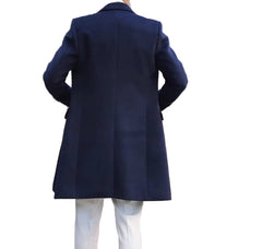 Person wearing a navy coat walking away from a building with wooden doors.