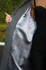 Close-up of a person wearing a gray coat with a black interior lining.