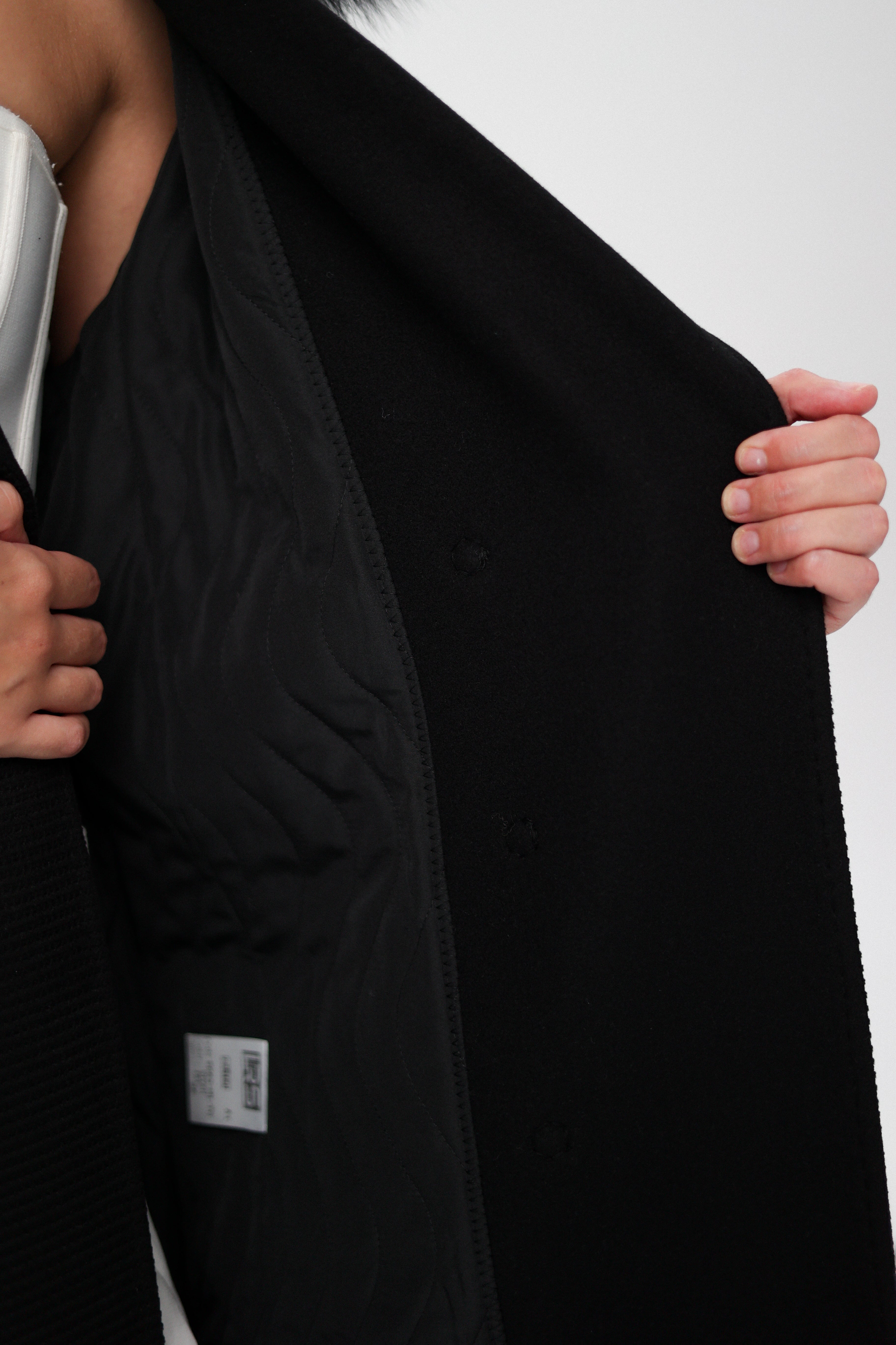 Close-up of a black coat with a silver buckle on a white background