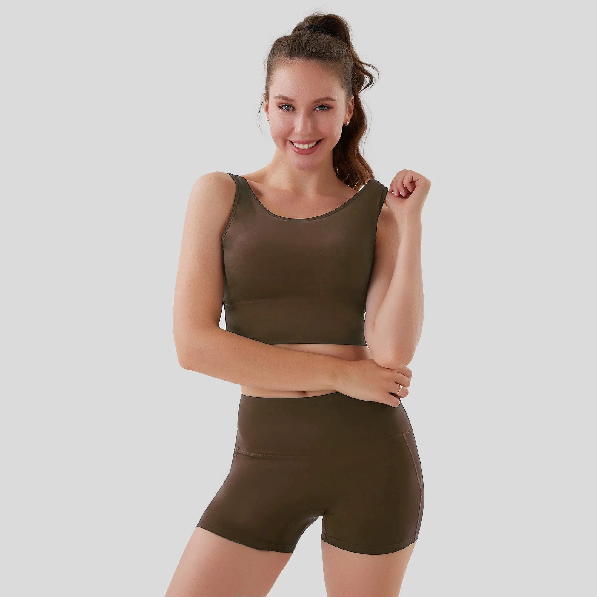 Woman wearing an olive green sports bra and shorts set on a light gray background