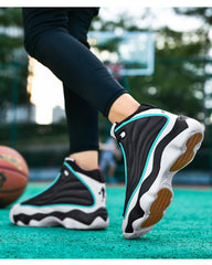 Person wearing black and white athletic shoes with brown soles on a sports court.