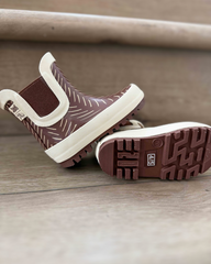 Pair of brown rain boots with white soles on a wooden floor.