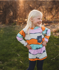 Young girl wearing a colorful sweater with a nature design outdoors.