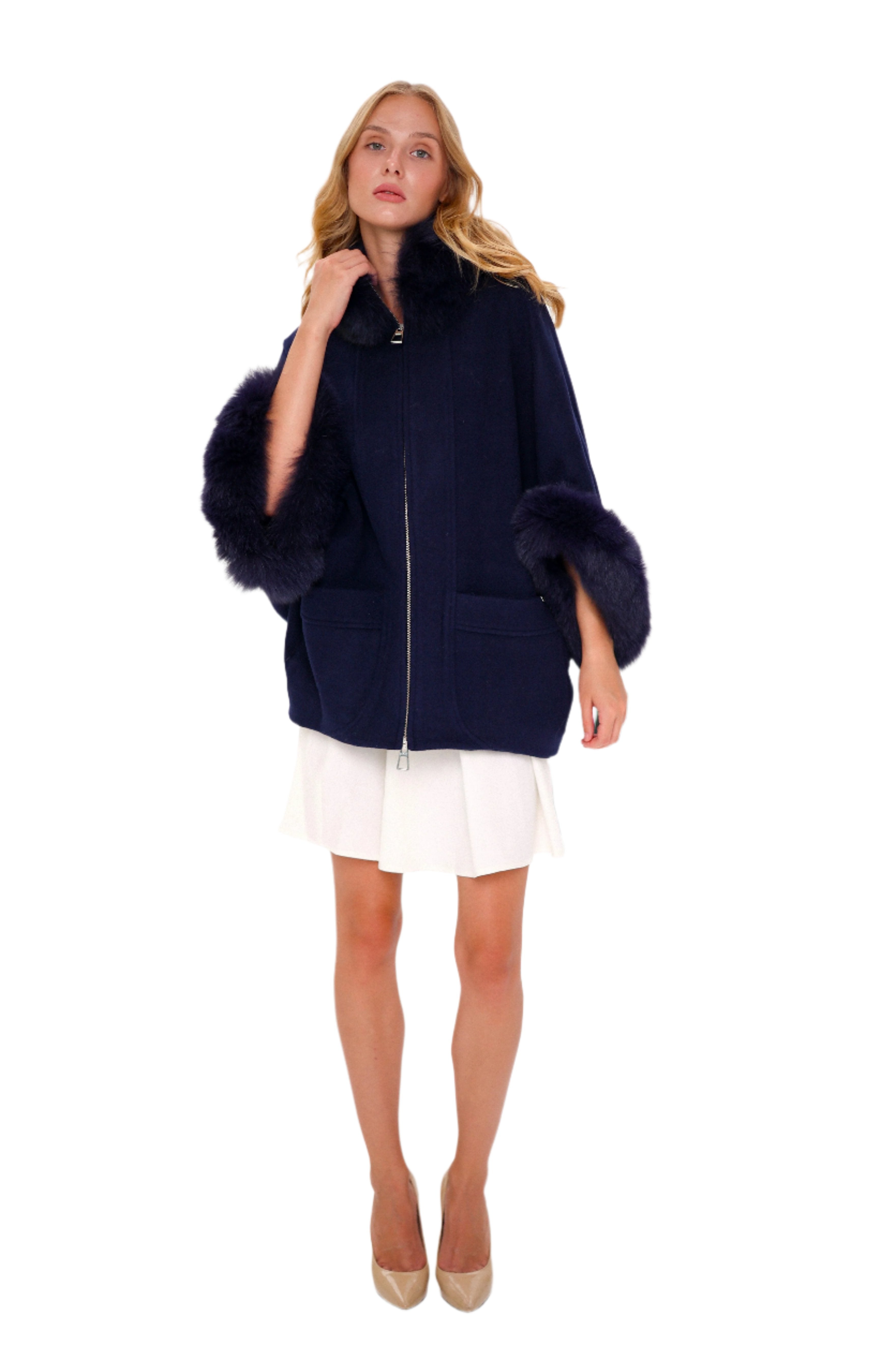 Woman wearing a navy blue poncho with fur trim on a white background