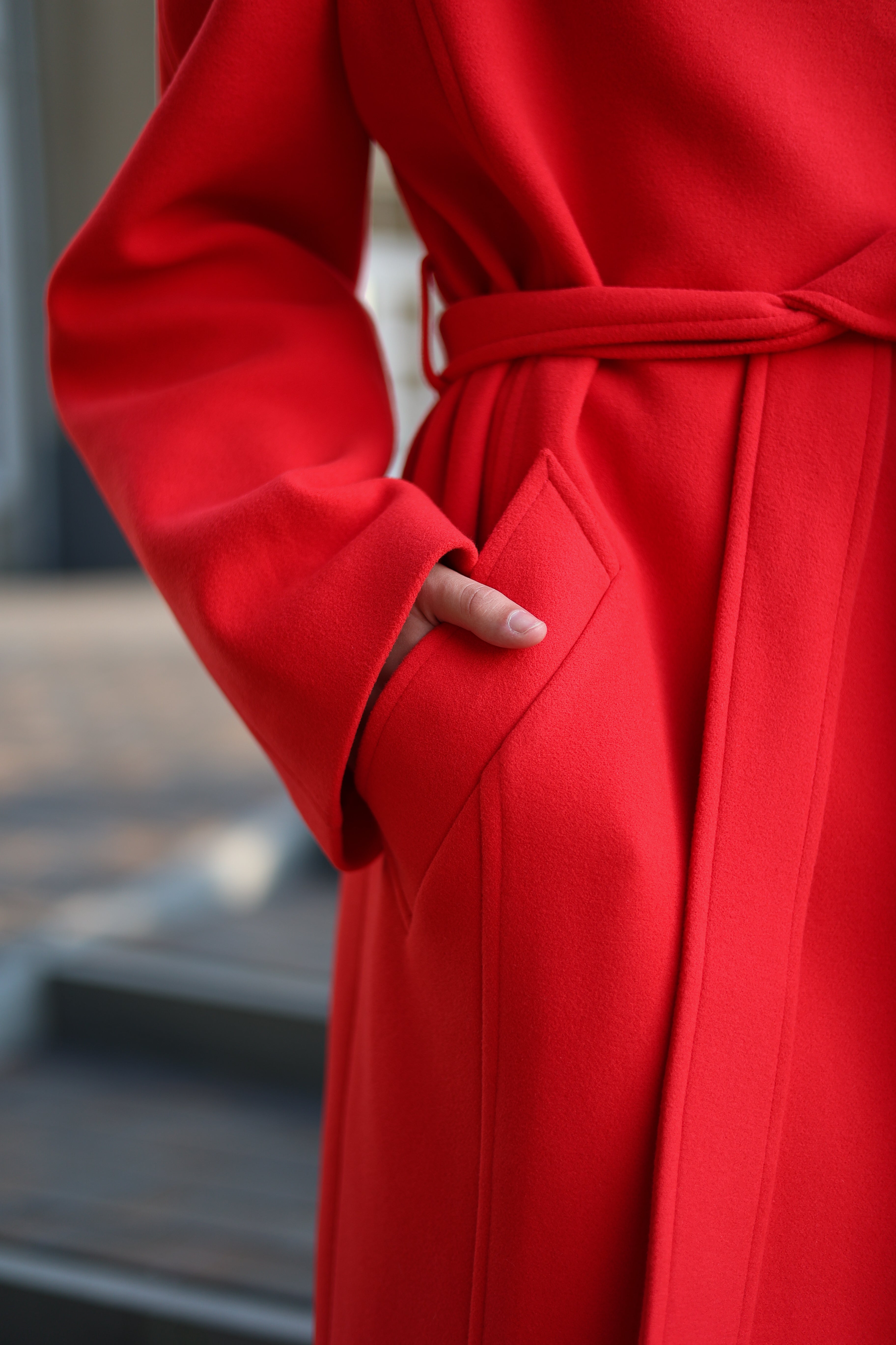 Woman in a red coat and white hat standing on steps outdoors