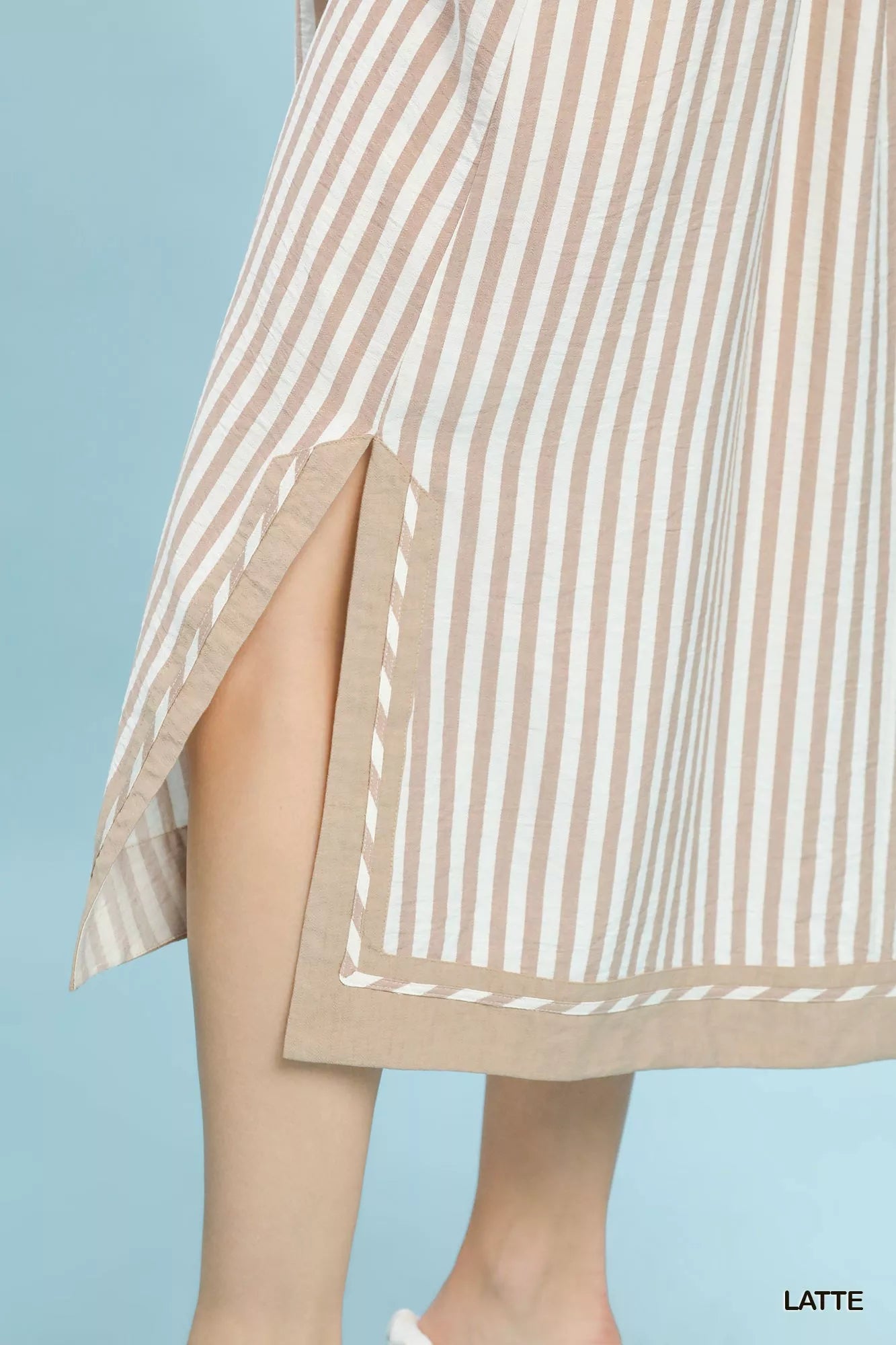 Beige and white striped dress with a slit on a light blue background