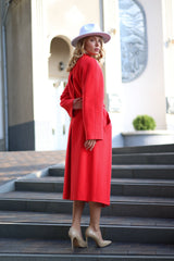 Woman in a red coat and white hat standing on steps outdoors
