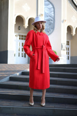 Woman in a red coat standing on steps with a building in the background