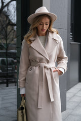 Woman wearing a beige trench coat and hat on a city street.