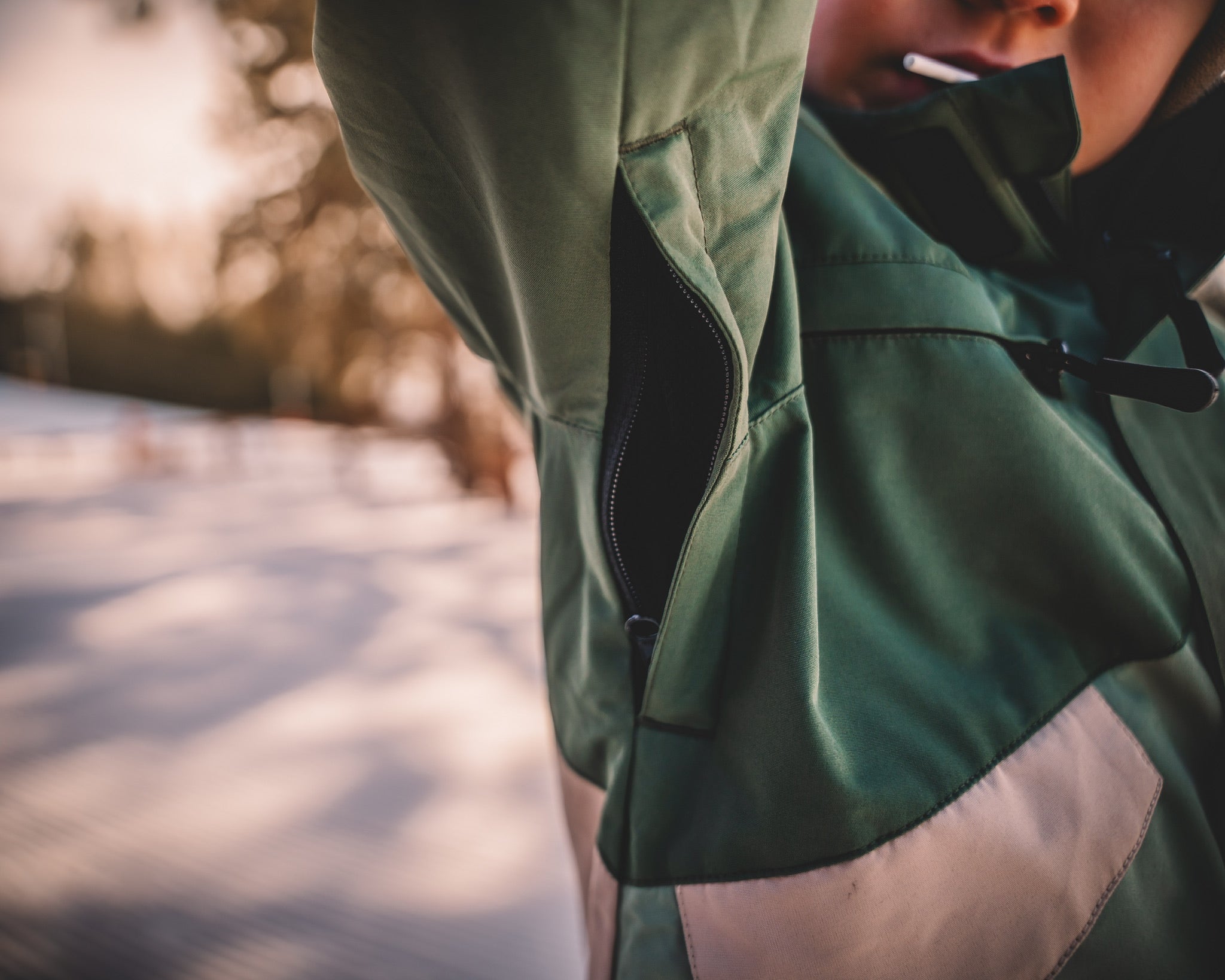 Close-up of a person wearing a green jacket with a blurred natural background
