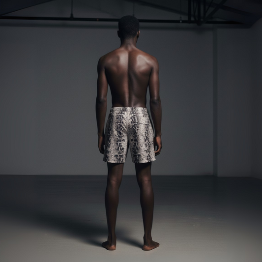 Man wearing patterned shorts standing against a dark background