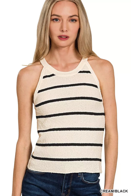 Woman wearing a cream and black striped tank top with blue jeans on a white background