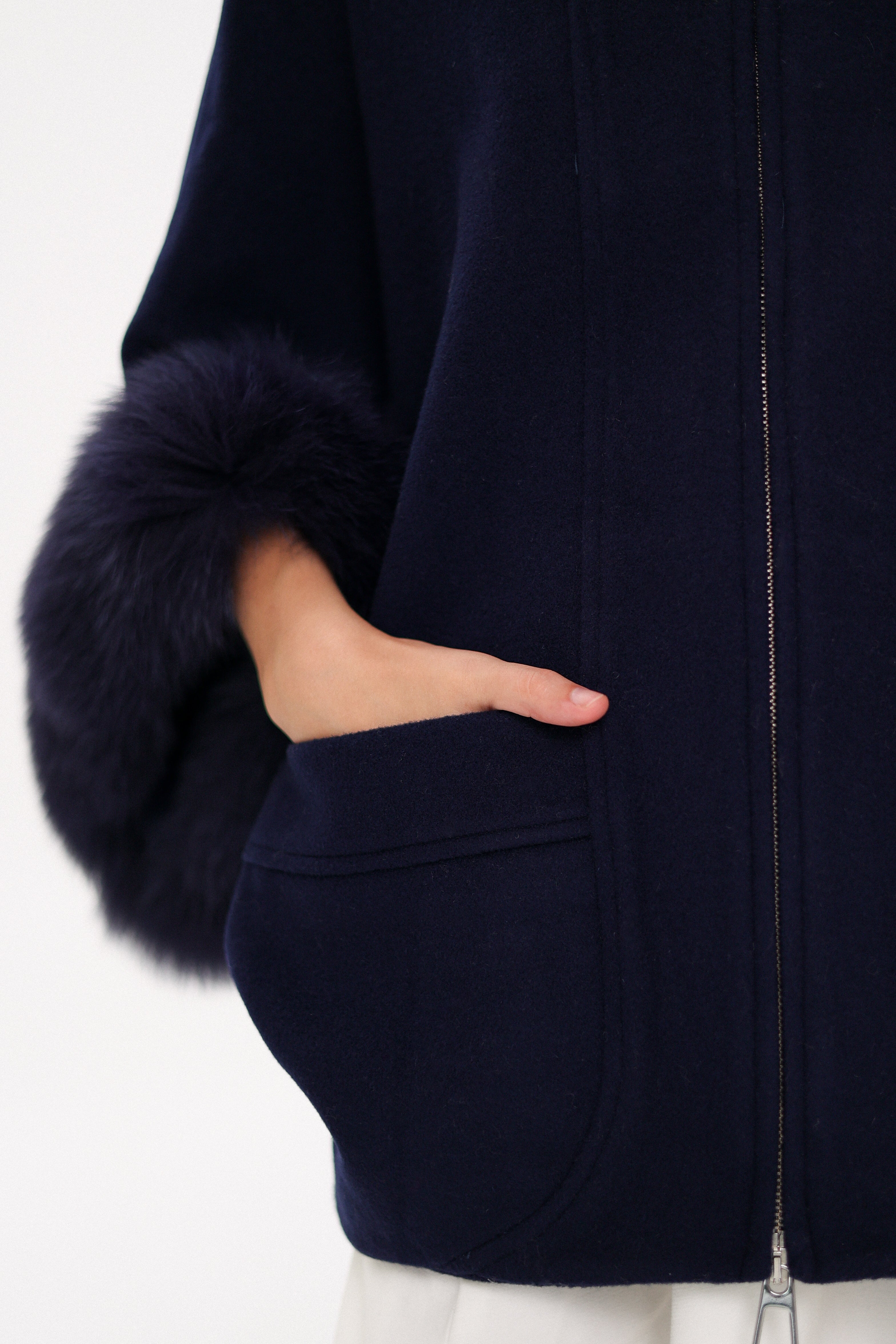 Navy blue coat with fur-trimmed sleeves on a white background