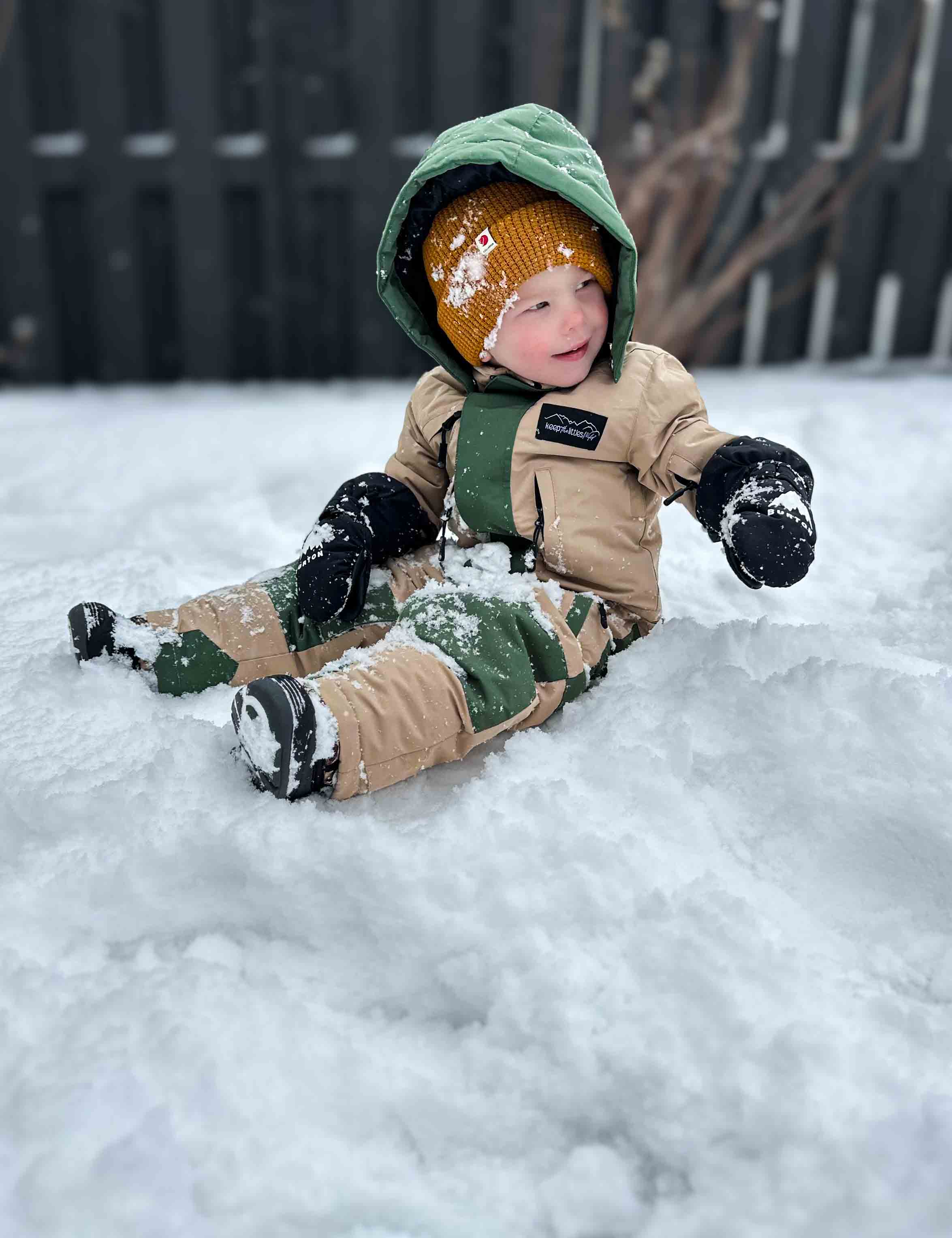 Child in winter clothing sitting in the snow