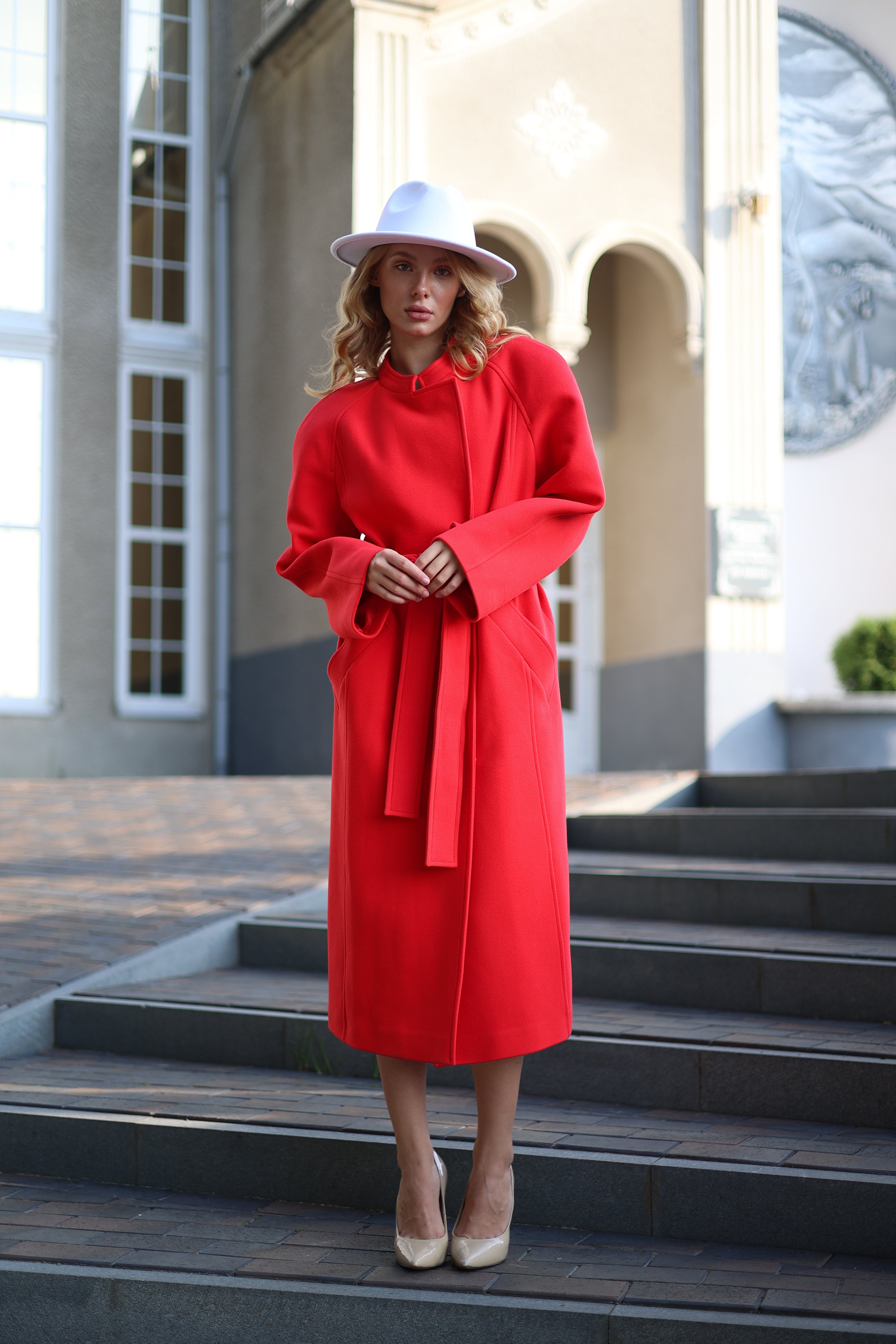 Woman in a red coat standing on steps outside a building