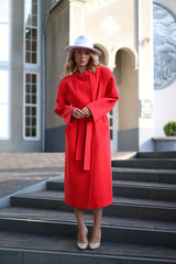 Woman in a red coat standing on steps outside a building