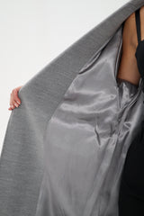 Woman wearing a gray coat over a black outfit on a white background