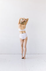 Person wearing a white bikini standing against a white background